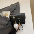 Detail of minimalist black crossbody bag with golden clasp and white pompom charm - Black With Pendant