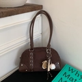 Close-up of retro brown bowling bag with suede texture and sports charms on white wall - With Baseball Charm / Brown