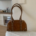 Detailed close-up of brown suede Boston bag with silver grommets and woven leather details - Without Pendant / Brown