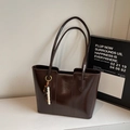 Detalle de bolso tote marrón oscuro brillante con colgante de cuentas y diseño elegante - Café Con Amuletos