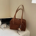 Detail of deep brown suede bowling bag with shoulder straps and plush puppy charm - Brown with Pendant