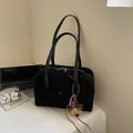 Detail of black suede bowling bag with dual zippers and plush dog charm on white desk - Black With Pendant