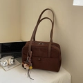 Close-up of brown suede hobo bag with top zipper and cute puppy charm on desk - Coffee With Pendant