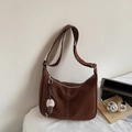 Detail der braunen Vintage Hobo-Tasche mit weißen Nähten und Plüschanhänger am Schreibtisch - Mit Anhänger / Braun