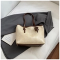 Gros plan détaillé d'un sac cabas en cuir crème texturé avec bordures marron et petit charme - Blanc Cassé