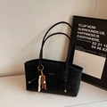 Dettaglio borsa tote nera opaca con manici sottili e ciondolo decorativo in legno - Nero