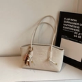 Dettaglio ravvicinato di una borsa tote in pelle color crema con un ciondolo boho di perline - Bianco Sporco