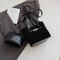 Detail view of black faux suede bucket bag with matching pouch and metal buckle on office blazer - Black