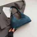 Dunkelblaue Wildleder-Schultertasche mit Metallfüßen auf einem Blazer-Hintergrund - Blau