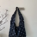 Detailed view of black polka dot satin tote bag with wide shoulder strap and soft texture - Black