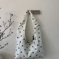 Detail shot of white satin tote bag with black polka dots and minimalist integrated strap - White