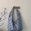 Detail of light blue polka dot satin hobo bag hanging on a boutique wall hook - Blue