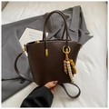 Detail einer dunkelbraunen Eimertasche mit Litschi-Struktur und goldenen Beschlägen - Kaffee Mit Anhänger