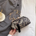 Elegant black shell bag with floral embroidery, gold metal handle, and tassel detail - Black