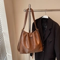 Detail of vintage brown drawstring bucket bag with oily leather texture hanging in window light - Brown No Pendant