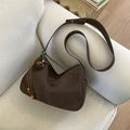 Detail of dark brown faux suede hobo bag with tassel wood bead charm on a sofa - Coffee with Pendant