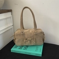 Detail einer beigen Wildlederhandtasche mit Kordelzug-Schleife auf einem Buch - Khaki