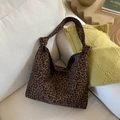 Detail of leopard print canvas tote bag with knotted handle on a soft beige fabric sofa - Green