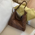 Detail of leopard print canvas tote bag featuring a knotted strap design on a soft sofa - Brown