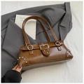Dettaglio della borsa baguette vintage marrone con rivetti metallici su un blazer grigio elegante - Marrone