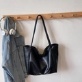Bolso tote negro clásico con asas largas y hebilla magnética en un entorno cotidiano - Negro
