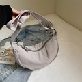 Bolso medialuna minimalista morado claro con correa ajustable en un fondo informal - Gris