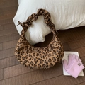 Detail der Schultertasche mit Leopardenmuster und Faltenriemen auf weißem Kissen - Braun