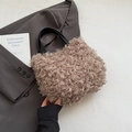Schicke beige Plüsch-Beuteltasche mit schwarzem Ledergriff auf grauem Blazer - Khaki