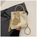 Detail of cream bucket bag with lychee texture, brown straps and cute dog charm pendant - Off White