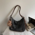 Detail van de grijze leren shopper met bruine riemen en een pluche hondenbedeltje - Zwart Met Hanger