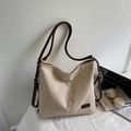 Gros plan détaillé du sac cabas en toile beige avec étiquette en cuir marron et bandoulière - Blanc Cassé
