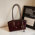 Detalle de bolso tote con estampado de leopardo, colgante de raqueta y logo dorado - Burdeos