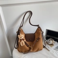 Close-up of caramel suede tote bag featuring smooth leather flap and cute plush bear charm - Brown (With Pendant)