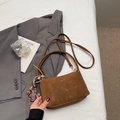 Detailed shot of brown faux suede bucket bag with beaded charm and metal logo accents - Coffee With Charms