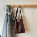 Detailansicht einer dunkelbraunen gewebten Tragetasche an einer Holzgarderobe - Kaffeebraun