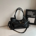 Detaillierte Nahaufnahme einer schwarzen glänzenden Schultertasche mit Tunnelzug und Metallösen - Schwarz