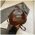 Bruine leren halve maan tas met hart hanger en gouden details op een grijze blazer - Bruin