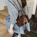 Retro dark brown oil wax leather handbag with charms on a model in indoor setting - With Pendant / Dark Brown