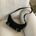 Detailed macro view of black suede hobo bag with silver buckle straps on a white sofa - Black