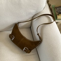 Close-up of brown suede moon bag with silver hardware on a white textured sofa - Brown