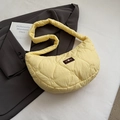 Dettaglio borsa gialla trapuntata con motivi a cuore su blazer grigio e libro decorativo - Giallo
