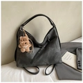 Détail d'un sac à dos vintage en cuir gris avec un pendentif d'ours en peluche brun - Noir avec pendentif
