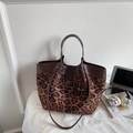 Detail of leopard print tote bag featuring brown leather trim and dual carrying straps - Leopard Print