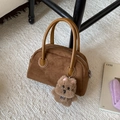 Dettaglio di una borsa bowling in camoscio marrone con ciondolo a cucciolo su tappeto - Marrone