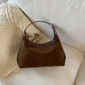 Dettaglio della borsa hobo in pelle scamosciata marrone scuro su un divano con maglione crema - Marrone