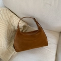Dettaglio borsa hobo in camoscio marrone su divano crema con maglione di maglia - Marrone