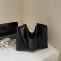 Nahaufnahme der schwarzen Tote-Bag mit Kettenriemen und geprägtem modischen Logo - Schwarz