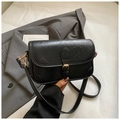 Detail shot of black leather texture crossbody bag with light gold buckle and flap - Black