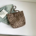 Dettaglio ravvicinato della borsa zebrata con logo in metallo dorato e trama in tessuto morbido - Zebra Marrone