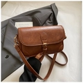 Close-up of brown faux leather texture and gold buckle hardware on a retro handbag - Brown